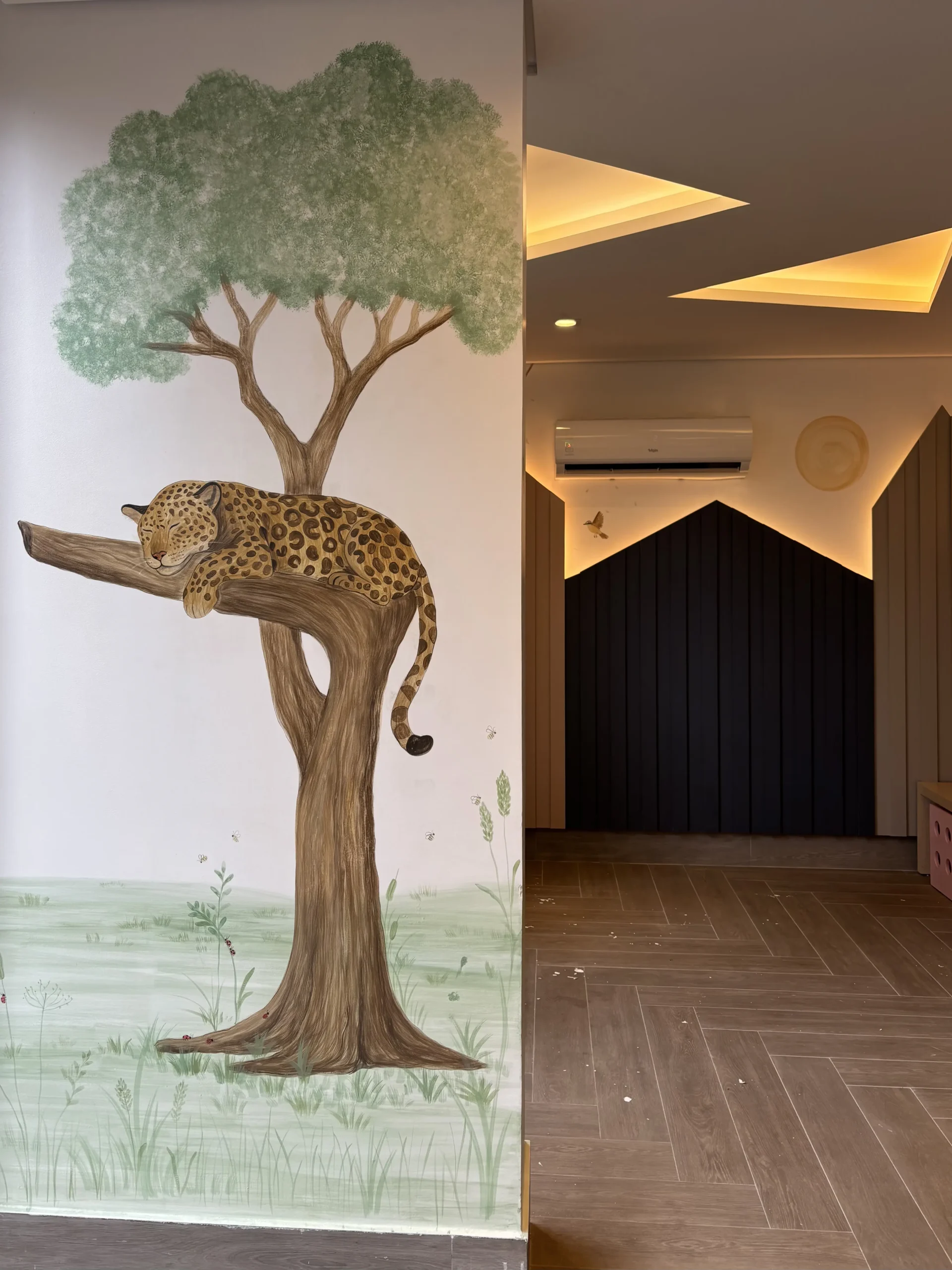 Onça descansando em um galho de árvore pintado em um espaço infantil
