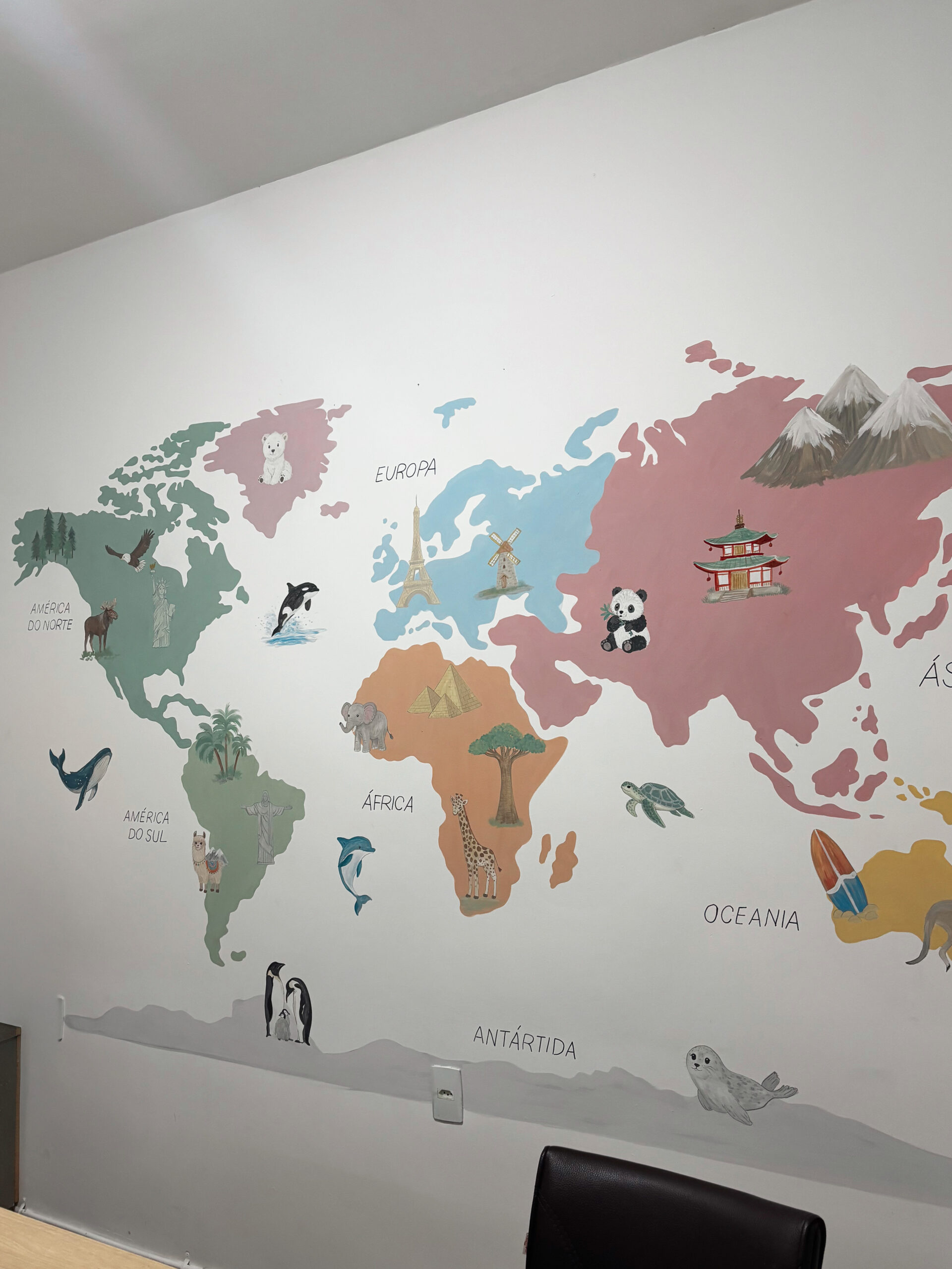 Mapa-múndi pintado à mão com continentes coloridos e animais de diferentes regiões