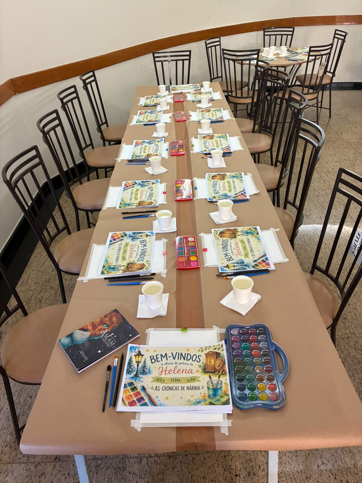 Mesa longa montada com kits de pintura, um lugar para cada participante