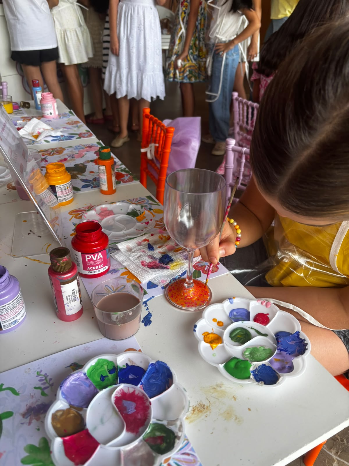 Criança pintando uma taça de vidro durante uma festa